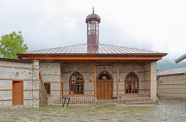 Мечеть Бедоюн с каменными стенами и деревянным балконом и мощёный двор в Лагиче.