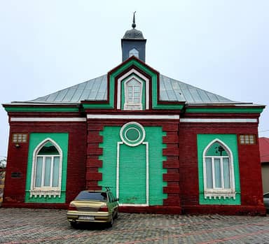 Ардебильская мечеть в Губе: красно-зелёный кирпичный фасад, стрельчатые окна и небольшая башенка на крыше.