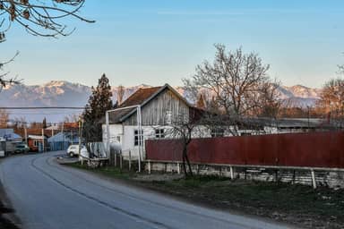 Сельская улица в Ивановке, деревянные дома и заснеженные горы вдали