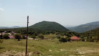 Лесистая гора возле Пиркули, сельские дома и луг на склоне, Шемахинский район
