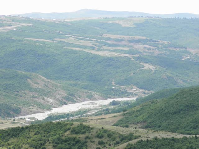 Ахсуйский район: долина Ахсучая, каменистое русло реки среди лесистых зелёных холмов