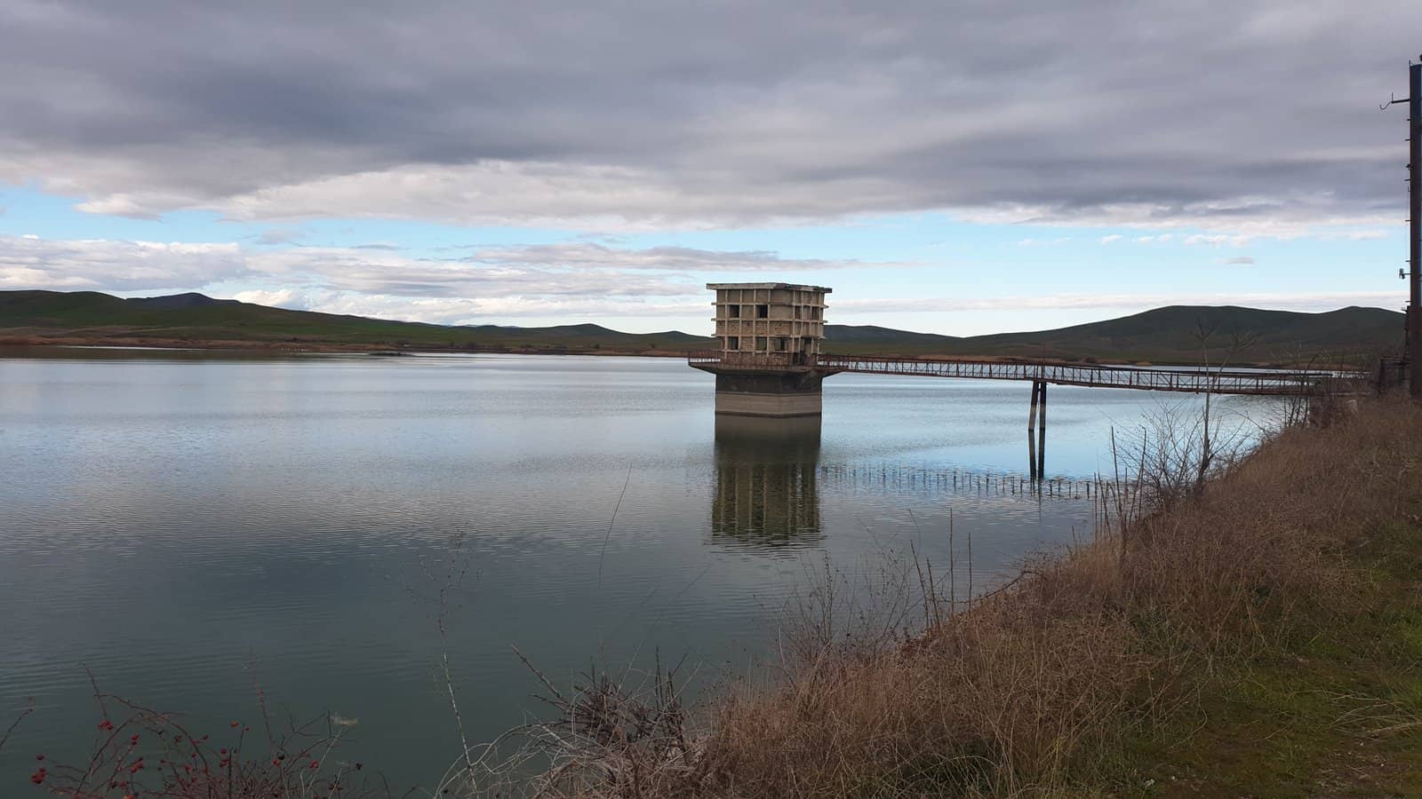 Нижнекенделенчайское водохранилище возле Физули: спокойная вода, водонапорная башня и облачное небо