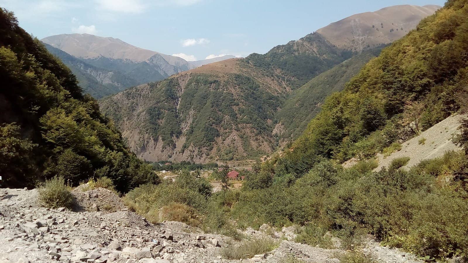 Qax rayonunda, İlisu yaxınlığında yaşıl yamaclı dağ dərəsi və daşlı çay yatağı.