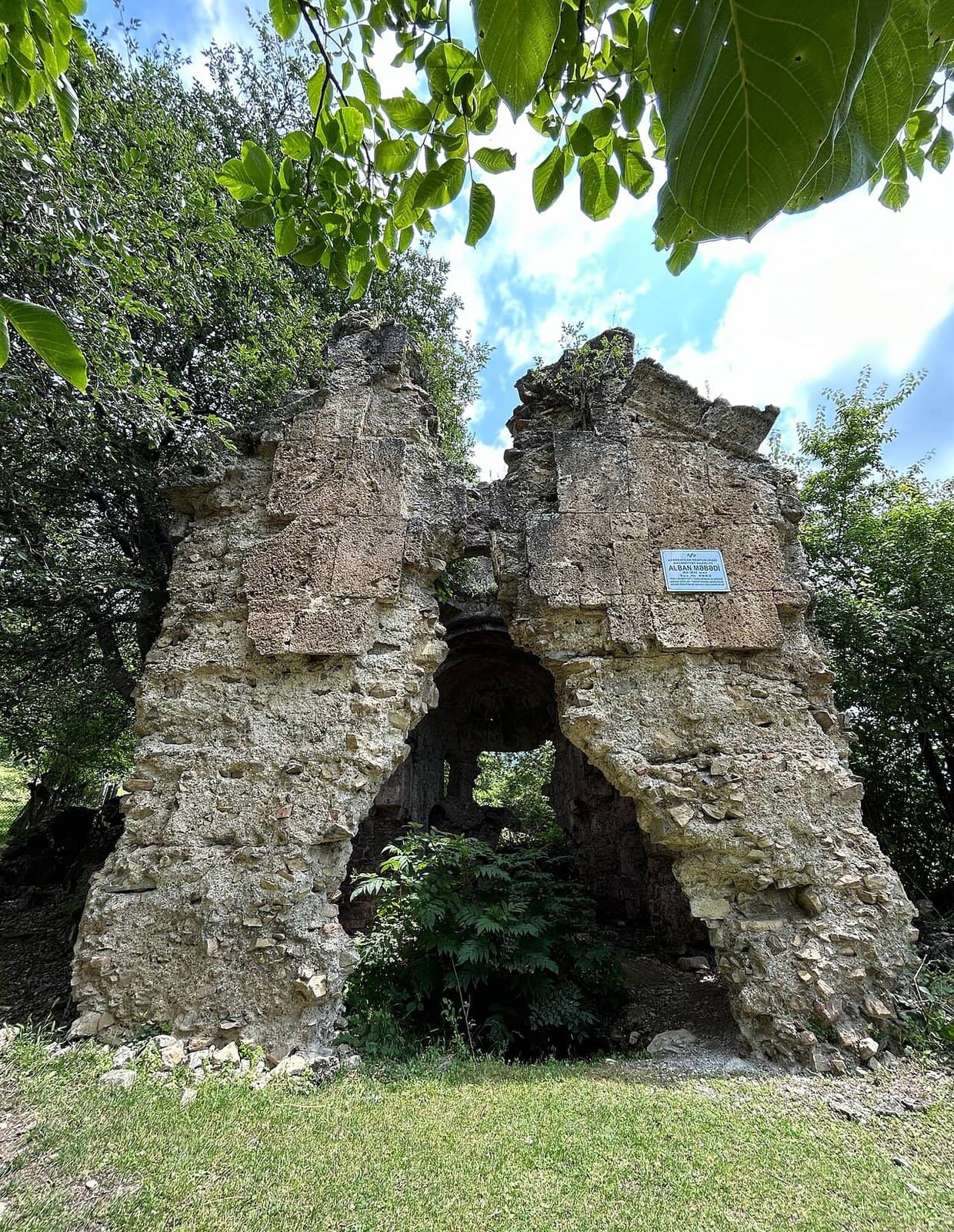 Ağaclar arasında Zəyzid kilsəsinin daş divar qalıqları.