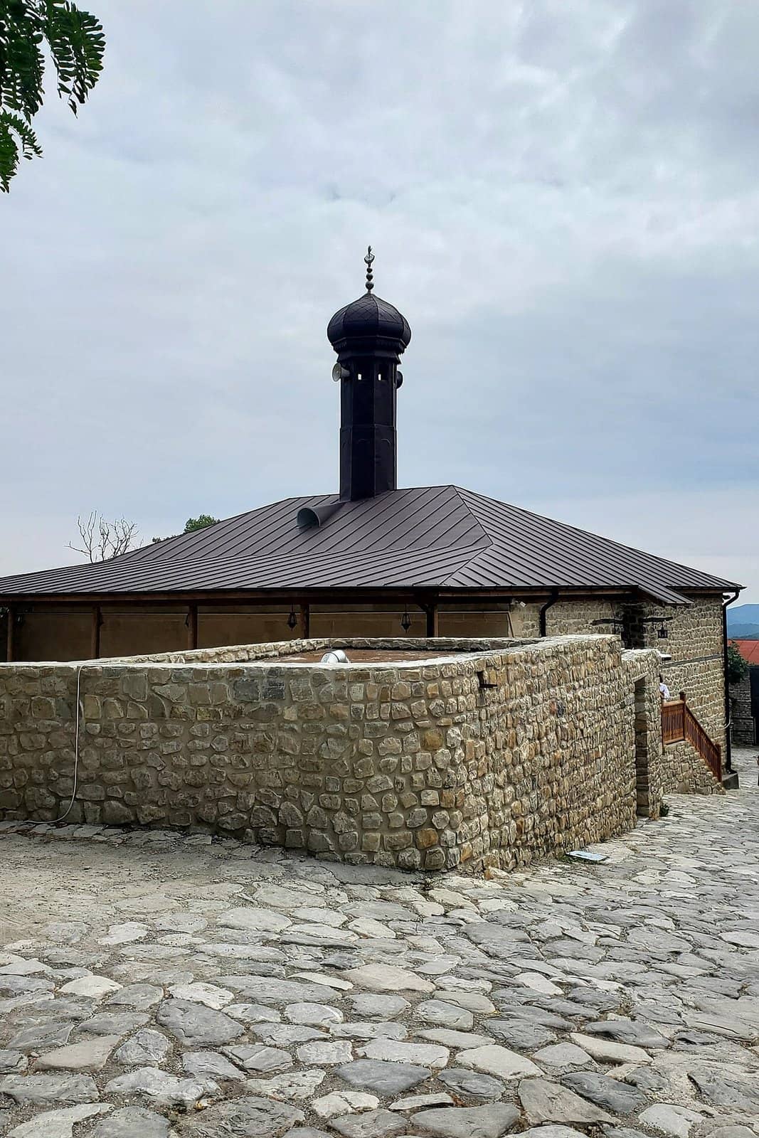 Basqalda daş hasarın arxasında qara minarəli Hacı Bədəl məscidi.