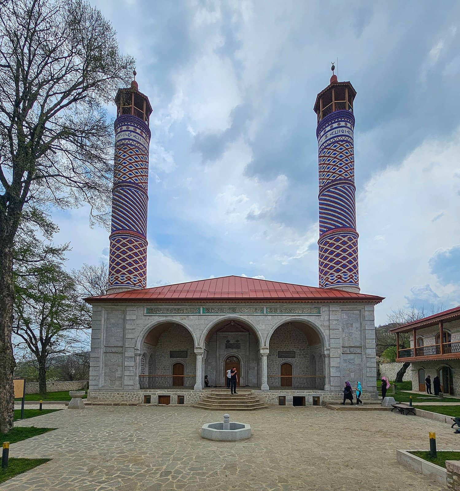 Yuxarı Gövhər ağa məscidi: üç tağlı daş fasad, qırmızı dam və iki hündür naxışlı minarə, önündə daş döşənmiş həyət