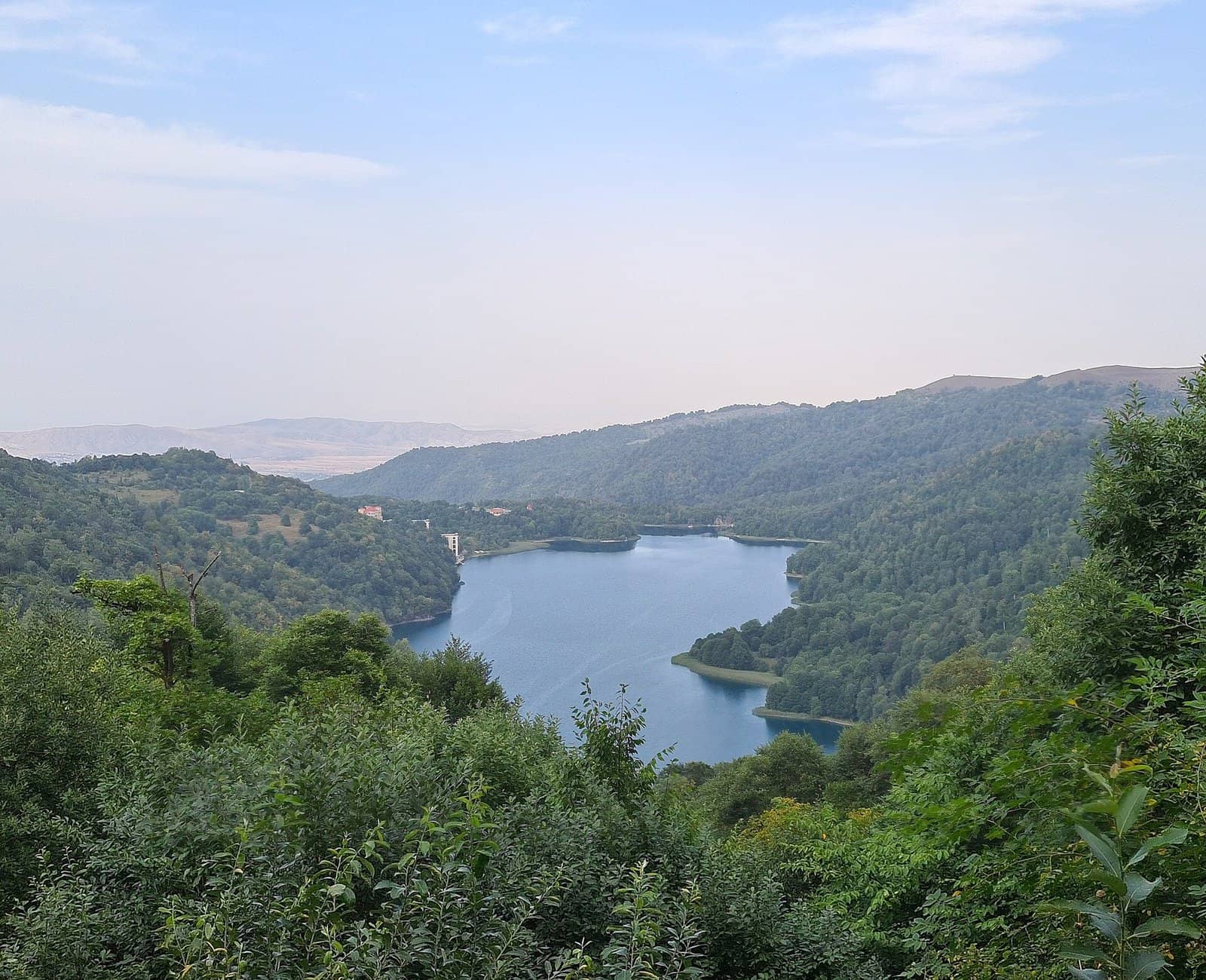 Meşəli dağlar arasında uzanan Göygöl gölü, ön planda yaşıl ağaclar