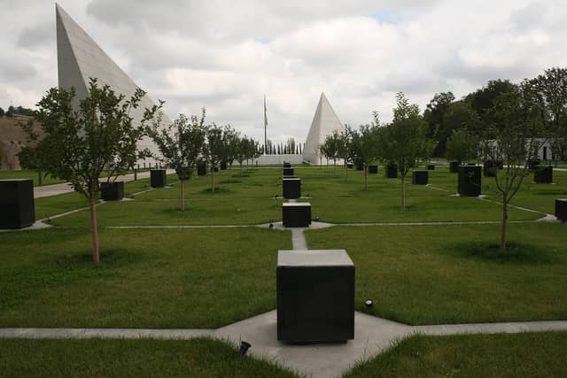 Quba Soyqırımı Memorial Kompleksində çəmənlikdə qara daş kublar, alma ağacları və iki ağ sivri beton konstruksiya.