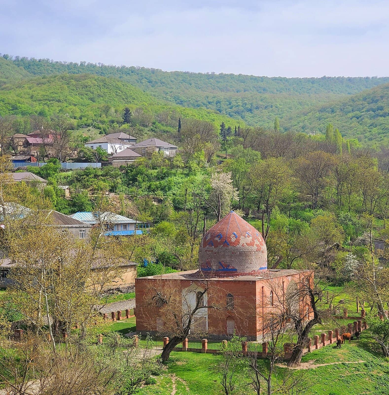 Həzrə kəndində meşəli təpələrin qarşısında naxışlı günbəzli Şeyx Cüneyd türbəsi.